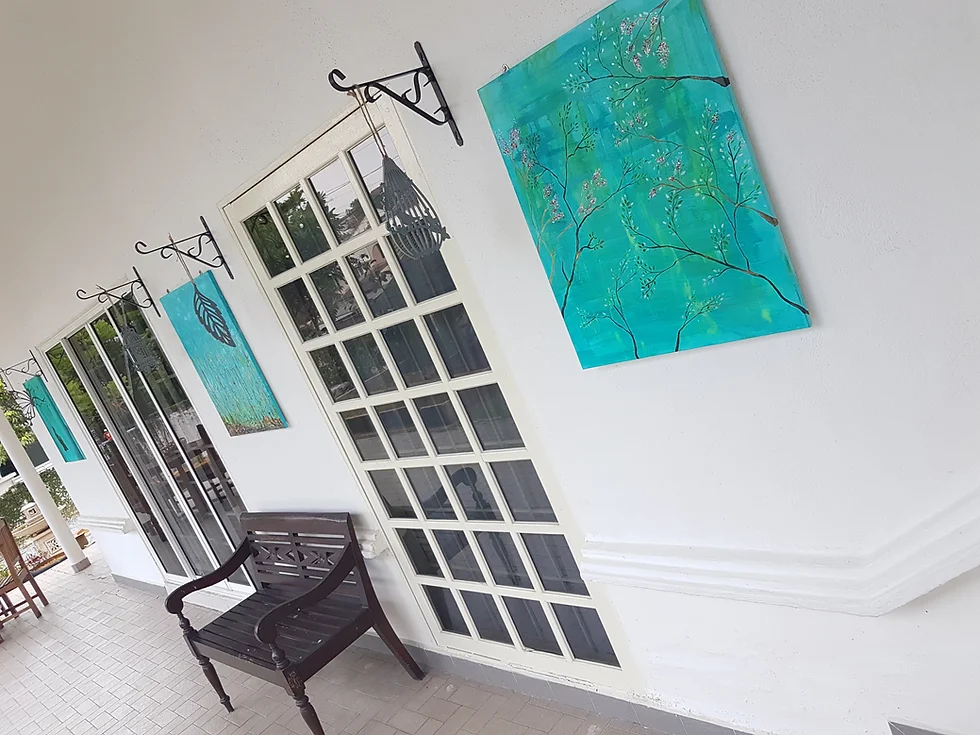 Covered walkway with teal painted artwork panels on a white wall, a wooden bench, and paned windows