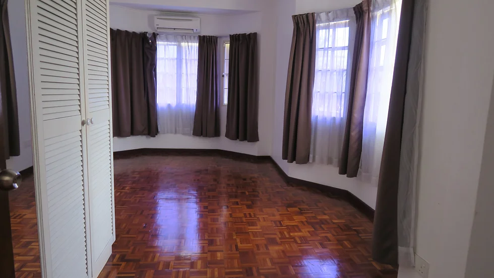Empty room with glossy parquet floor, brown curtains over windows, white louvered cupboard door, muted warm tones, calm